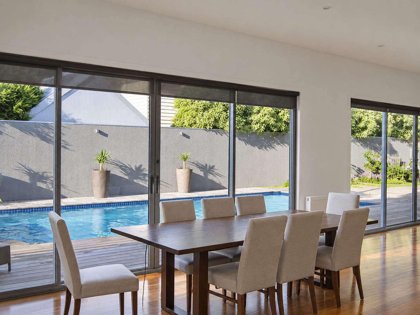 The dining table looking the length of the pool through full-height sliding doors