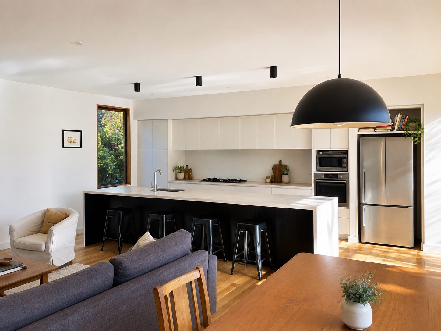 White cabinetry along the wall, black island bench, dome pendant over the table